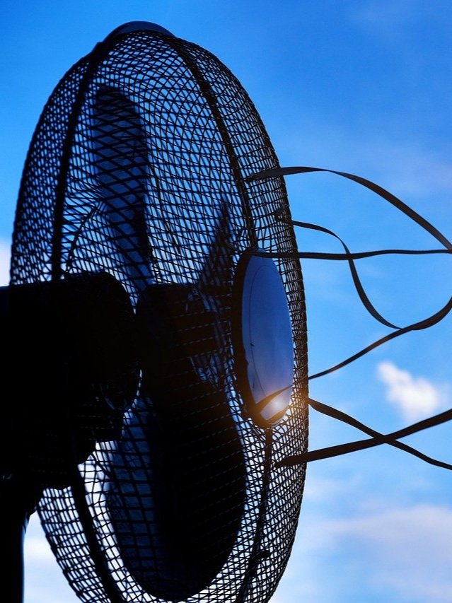 image of a fan blowing ribbon in the air with the sky and clouds as background