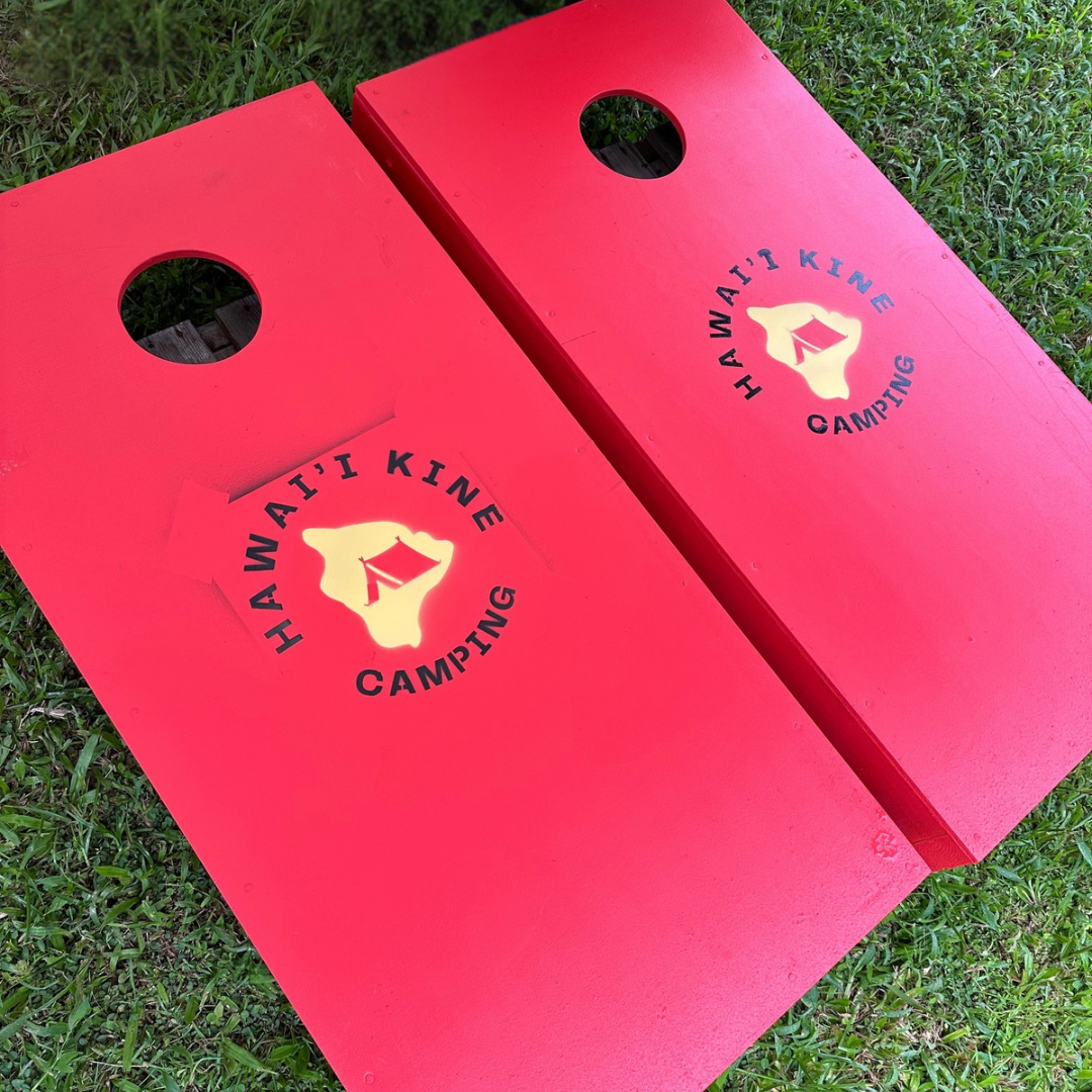 red corn holes board game with logo of Hawaii Kine Camping on them