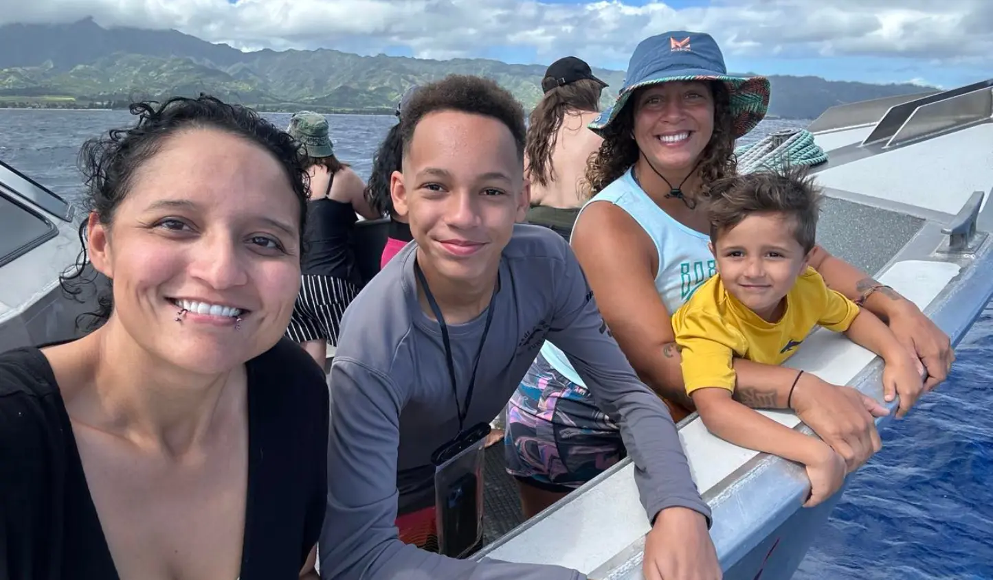smiling family on boat in hawaii ocean waters to go snorkeling beautiful skies and background of island